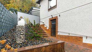 Ein Garten mit einer Steinstruktur, einem Holzzaun und einer Ziegelmauer.