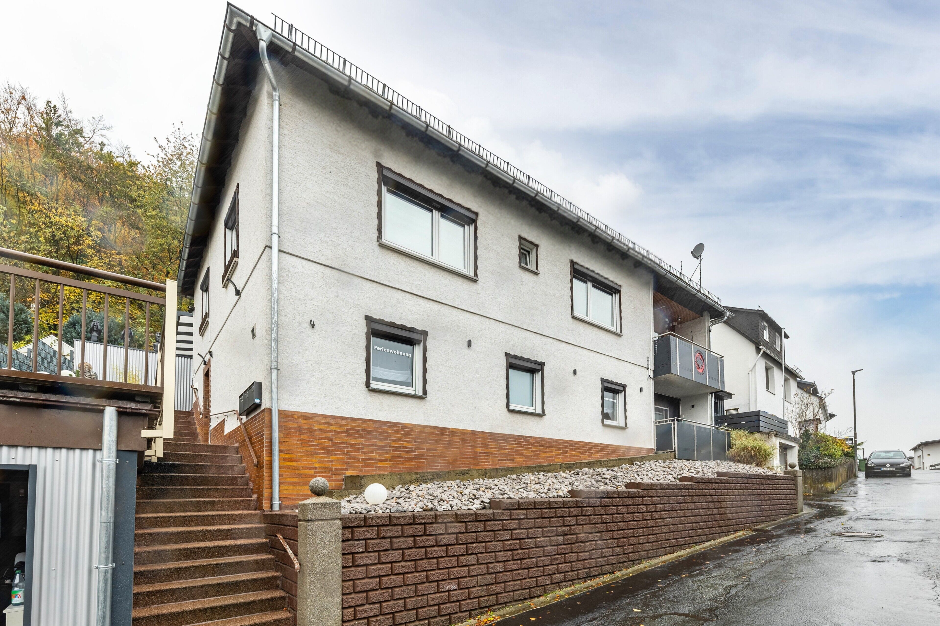 Ein mehrstöckiges Gebäude mit einer Ziegelbasis und weißen Obergeschossen, inklusive Balkon.