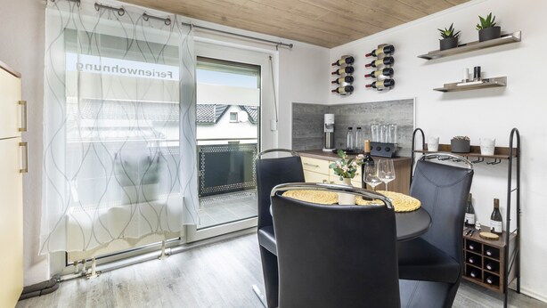 Eine moderne Küche mit Essbereich, ausgestattet mit einer Schiebetür aus Glas, einem Weinkühlschrank und Topfpflanzen.