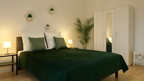 A bedroom with a bed, nightstands, a wardrobe, and a potted plant.
