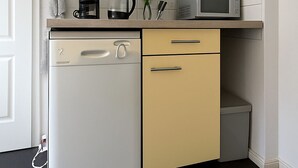 A compact kitchen with a dishwasher, microwave, and a small cabinet.