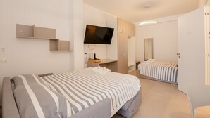 A modern hotel room with a bed, a TV, a mirror, and a wardrobe. - Agorà Vieste Rooms & Apartments (Vieste)