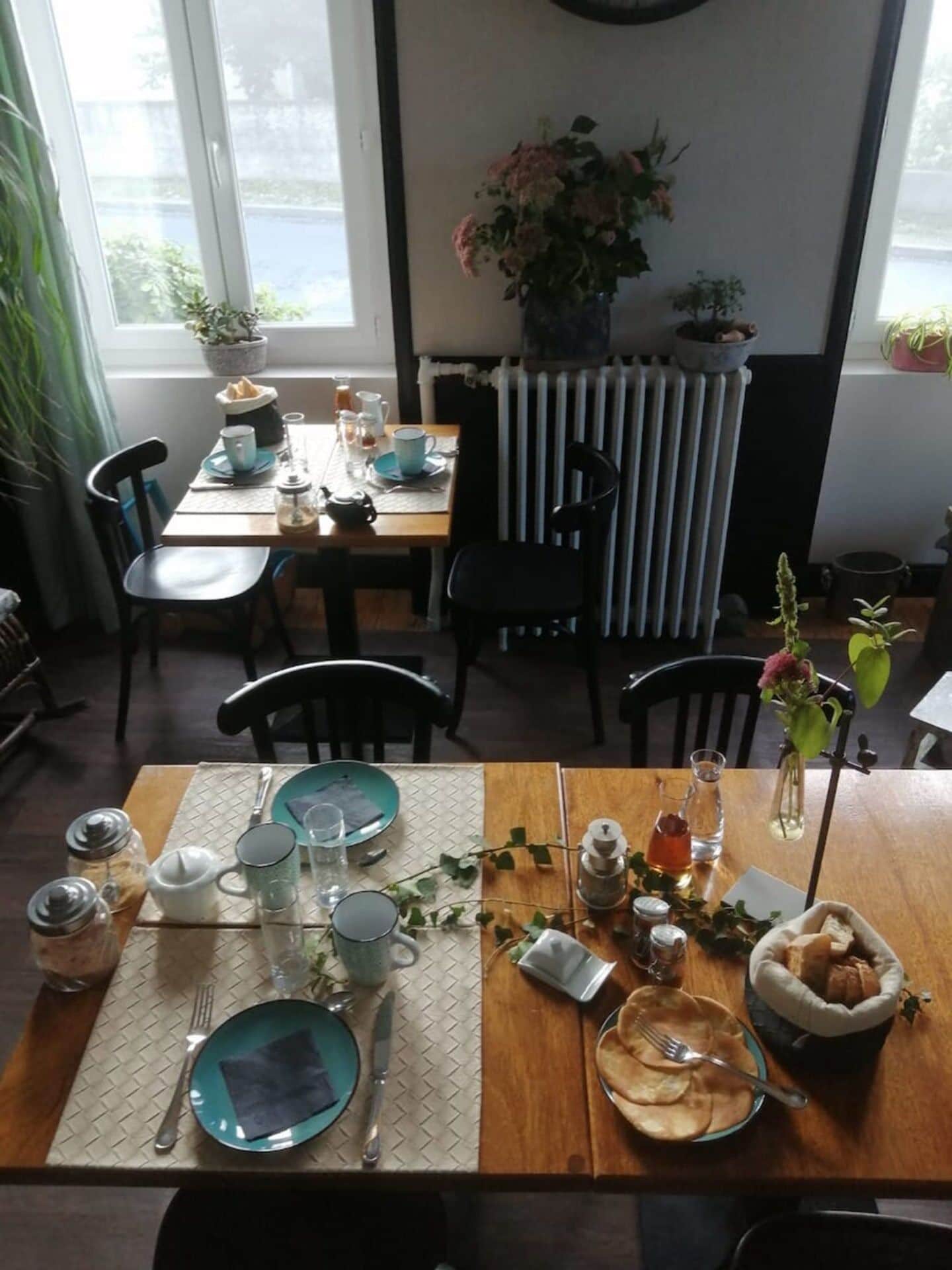 Comedor con una mesa dispuesta para dos, que incluye diverso menaje de mesa y un jarrón con flores.