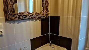 A bathroom with a white sink, a decorative woven mirror frame, and a bottle of hand soap.