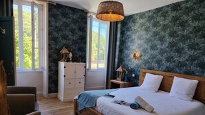 Un dormitorio con una cama de madera, un tocador blanco y una ventana con vistas a zonas verdes.