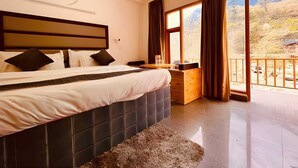 Une chambre à coucher avec un grand lit, une table de chevet en bois et une vue sur un paysage montagneux par une grande fenêtre.