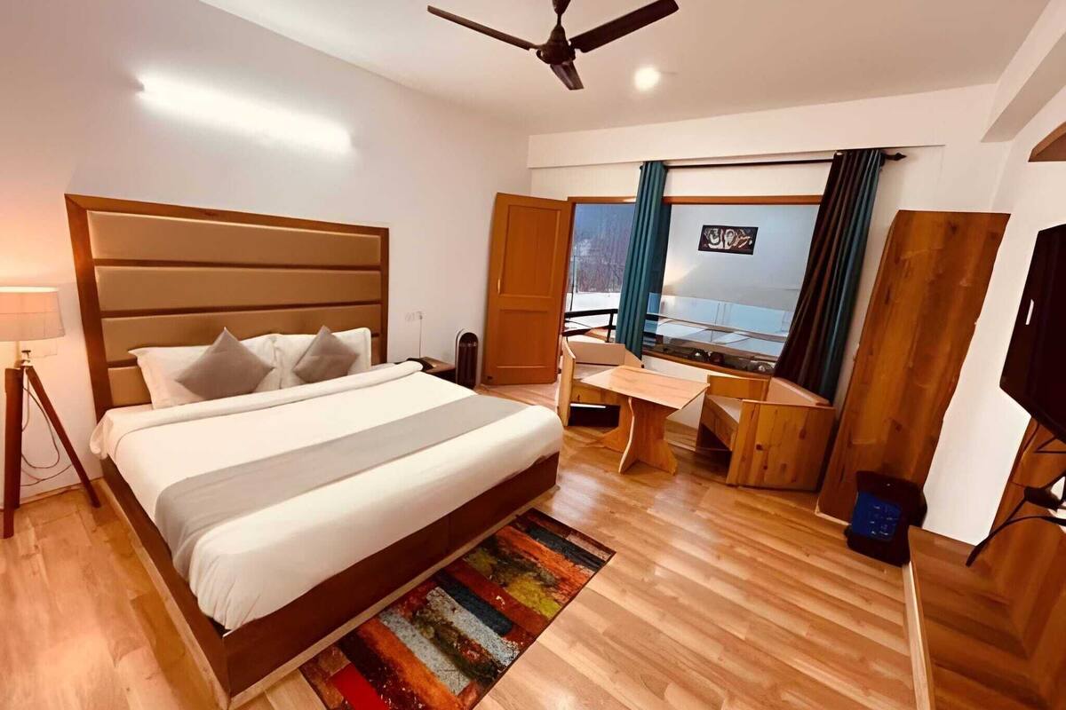 Une chambre d’hôtel moderne, dotée d’un grand lit, d’un bureau, d’une télévision et offrant une vue sur l’extérieur.