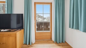A room with a wooden cabinet, a television, and a window with curtains.