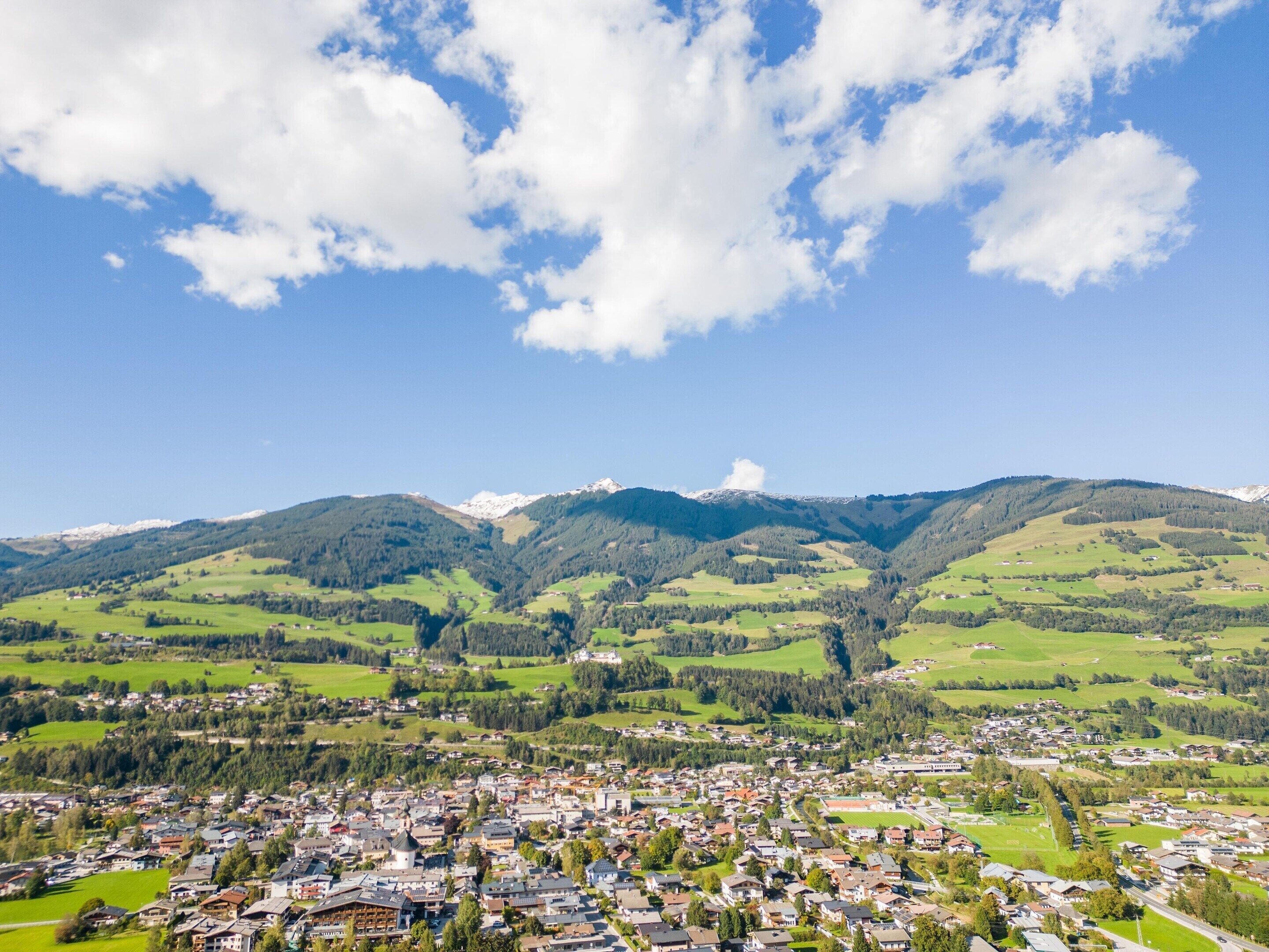 A town nestled in a valley with a mountain range in the background.
