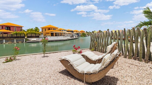 A poolside area with a lounge chair, a cactus garden, and a view of a marina with boats and buildings.