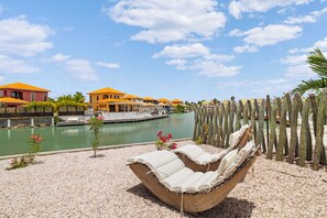 Ein Poolbereich mit Liegestuhl, Kakteengarten und Blick auf eine Marina mit Booten und Gebäuden.