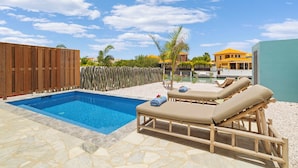 A swimming pool with lounge chairs and a wooden fence.