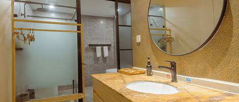Un baño con lavamanos de mármol, un espejo grande y una cabina de ducha de vidrio.