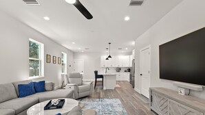 A modern living room with a sofa, coffee table, and a TV on a wooden cabinet. - NEW Casa Cereza - Stunning New Build In Old Tampa (Tampa)