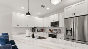 A modern kitchen with white cabinets, stainless steel appliances, and a marble countertop. - NEW Casa Cereza - Stunning New Build In Old Tampa (Tampa)