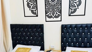 Habitación de hotel con dos camas, un cabecero oscuro y una pared con tres obras de arte de estilo blanco y negro.