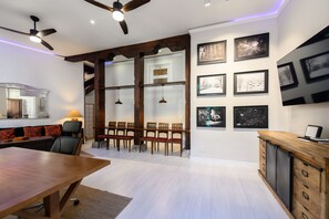 A modern kitchen with white walls, wooden beams, and a dining area with a long table and chairs.