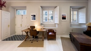 A room with a desk, office chair, and a brown leather chair. There are two windows with bars, a radiator, and a door with a handle. - M Pda2bi Loft DE Lujo DE Dise O Hist Rico A ES (Madrid)