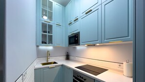 A modern kitchen with light blue cabinets, a stainless steel sink, a black microwave, and a built-in oven. - M Pda2bi Loft DE Lujo DE Dise O Hist Rico A ES (Madrid)