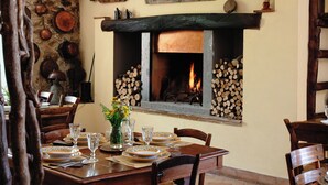 Un coin repas agrémenté d’une cheminée, de meubles en bois et d’œuvres d’art décoratives murales.