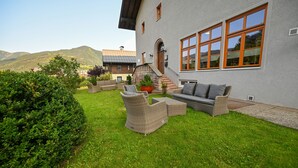Et hus med en patio med fletmøbler og en potteplante.