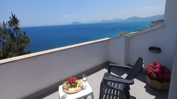 Un balcon avec une table dressée pour un repas, une chaise et un pot de fleurs.