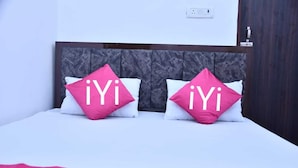 Un lit avec deux oreillers ornés du texte « iYi » et une tête de lit en bois foncé.