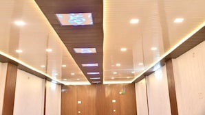 Un intérieur moderne avec un mur lambrissé en bois, un plafond doté d’un éclairage encastré et d’un écran numérique.
