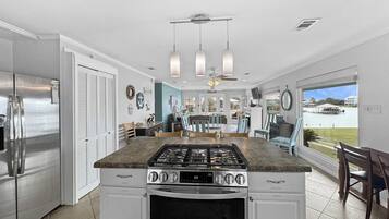 A modern kitchen with a central island, stainless steel appliances, and a view of a lake through the dining area.