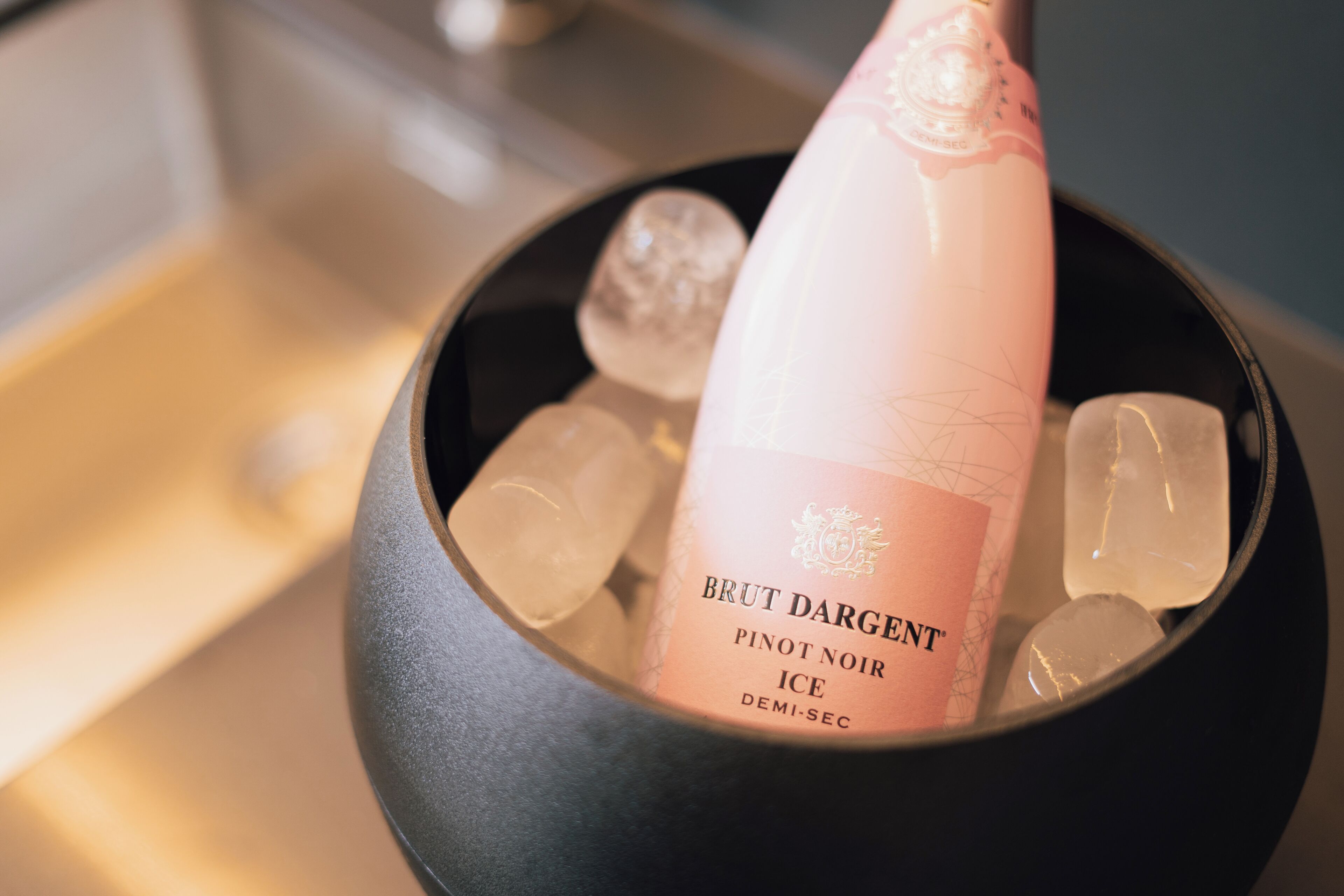 A bottle of Brut Dargent Pinot Noir Ice in a bowl with ice cubes.