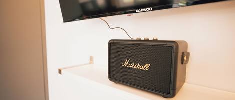 A Marshall speaker mounted on a white wall with a television above it.