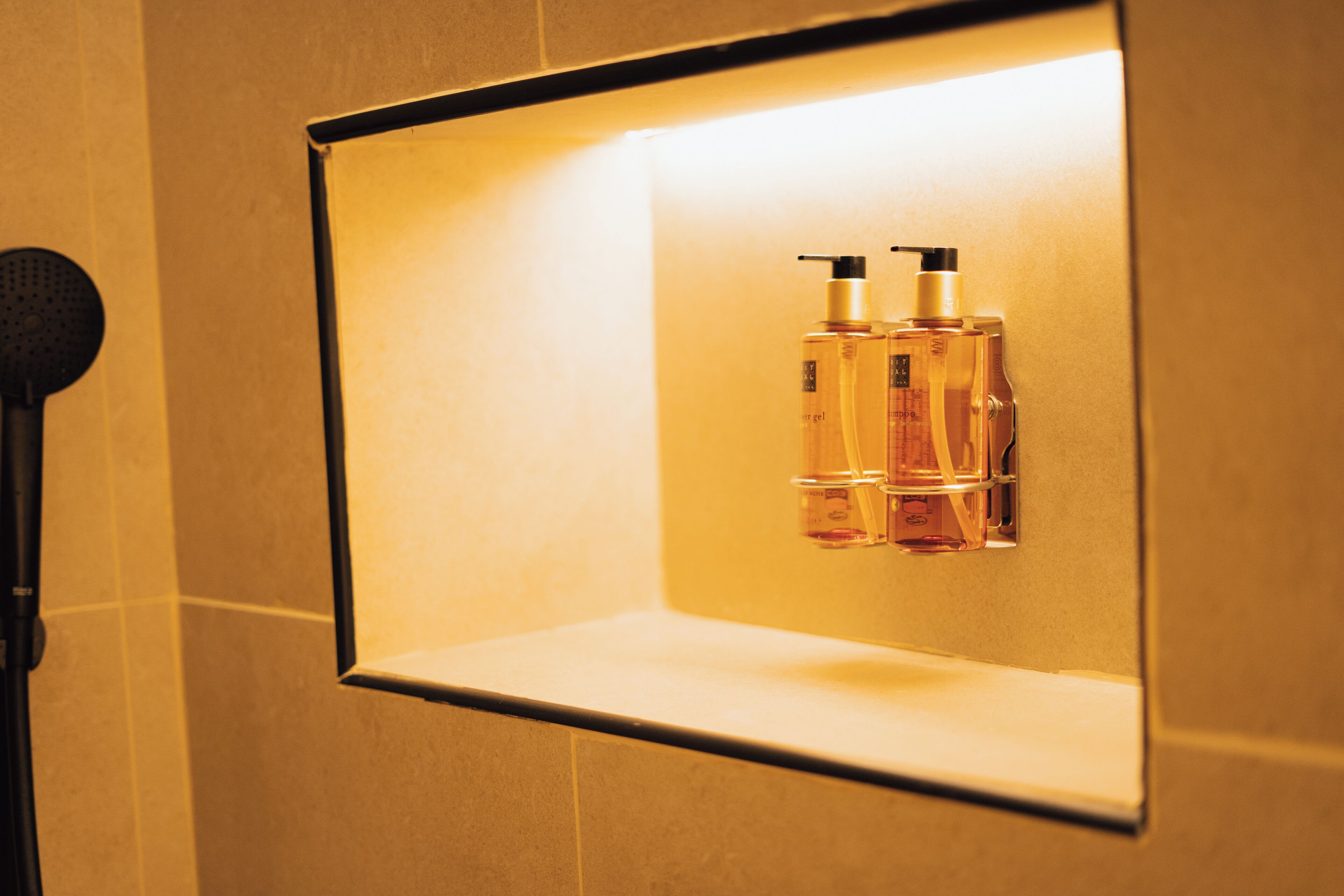 A bathroom with a mirror, two bottles of liquid soap, and a microphone.