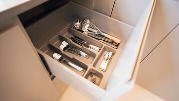 A drawer with various kitchen utensils including spoons, forks, and a whisk.
