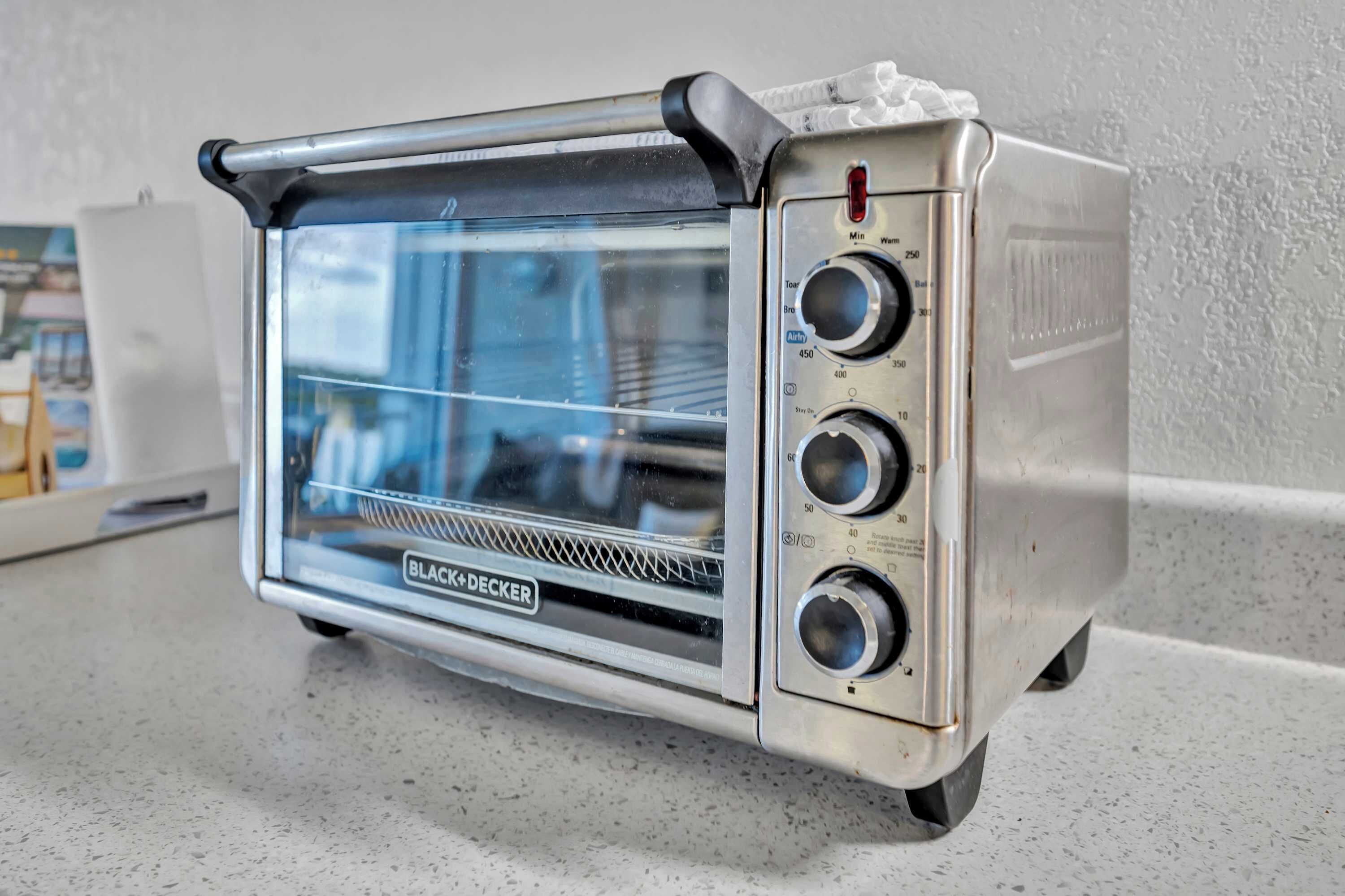 Un horno tostador BLACK+DECKER con pantalla digital, perillas de control y puerta de vidrio.