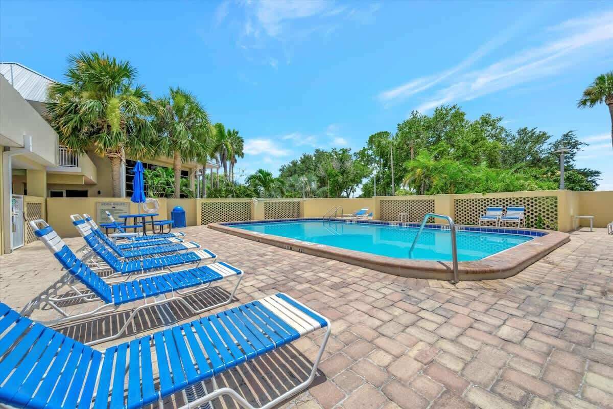 A swimming pool area with blue lounge chairs and a poolside table.
