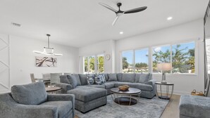 Un salon moderne avec un canapé d’angle, une table basse ronde et un ventilateur de plafond.