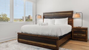 A modern bedroom with a wooden bed, white bedding, and two bedside lamps. - NEW Casa Cielo - Gorgeous Newly Built Tampa Home (Tampa)