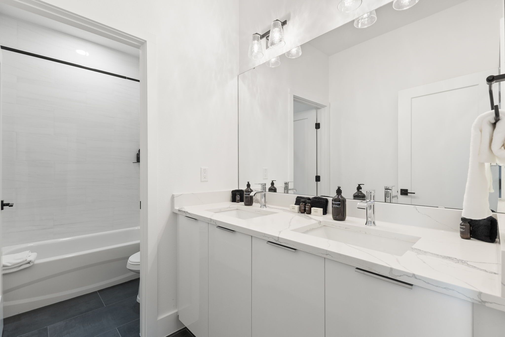 Ein modernes Badezimmer mit einem Doppelwaschbecken, einem großen Spiegel und einer Badewanne.