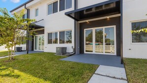 Une maison moderne à deux étages, dotée d’un patio couvert, de grandes fenêtres et d’une pelouse bien entretenue.