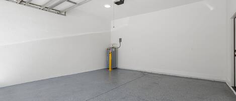 Ein geräumiger, leerer Raum mit hoher Decke, einem an der Decke befestigten Projektor und einem gelben Feuerlöscher auf dem Boden.