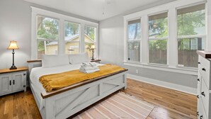 A bedroom with a bed, a ceiling fan, and large windows. - NEW Lakeland Landing Cute Bungalow by Downtown (Lakeland)