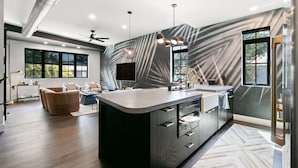 Une cuisine moderne dotée d’un îlot central, de grandes fenêtres et d’un ventilateur de plafond.