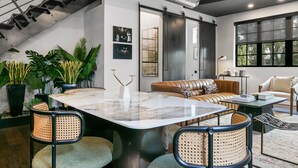 Un salon moderne avec une table basse en marbre, un canapé en cuir et des fauteuils en rotin.