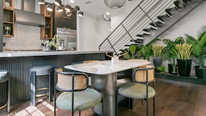 Une cuisine moderne avec un coin bar, un escalier et des plantes en pot.