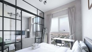 A hotel room with a large bed, a desk, and a balcony with a city view. - Dubai Hills Sleeps 2 With Private Balcony (Dubai)