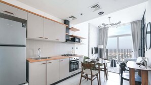 A modern kitchen with a dining area, large windows, and a view of the city. - Dubai Hills Sleeps 2 With Private Balcony (Dubai)