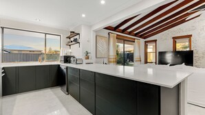 Una cocina moderna con una isla grande, armarios oscuros y vista al patio trasero.