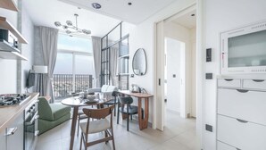 A modern kitchen with a dining area, a living space with a sofa and a TV, and a balcony with a view.