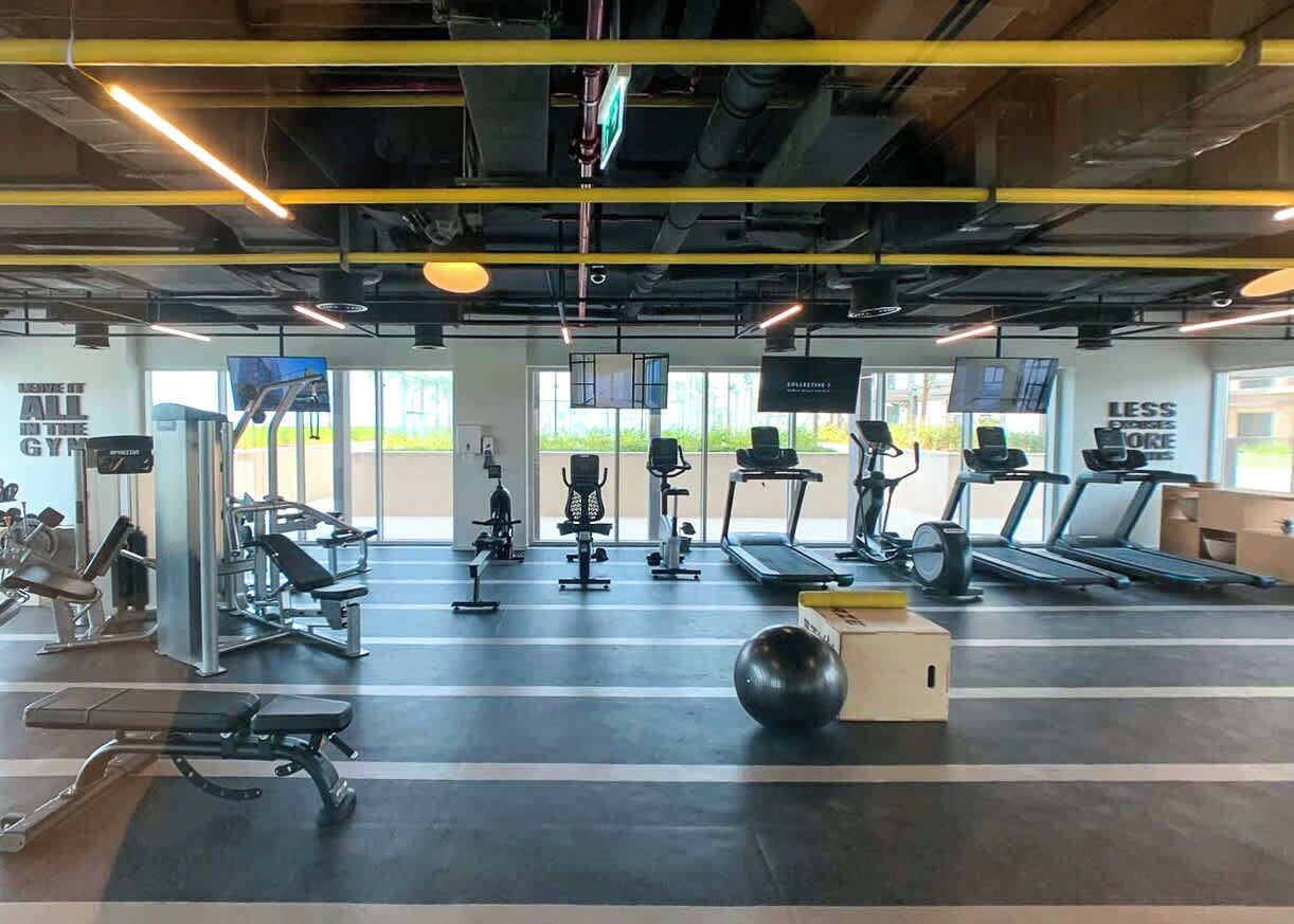 Een fitnessruimte met loopbanden, krachttrainingsapparatuur en een grote fitnessbal.