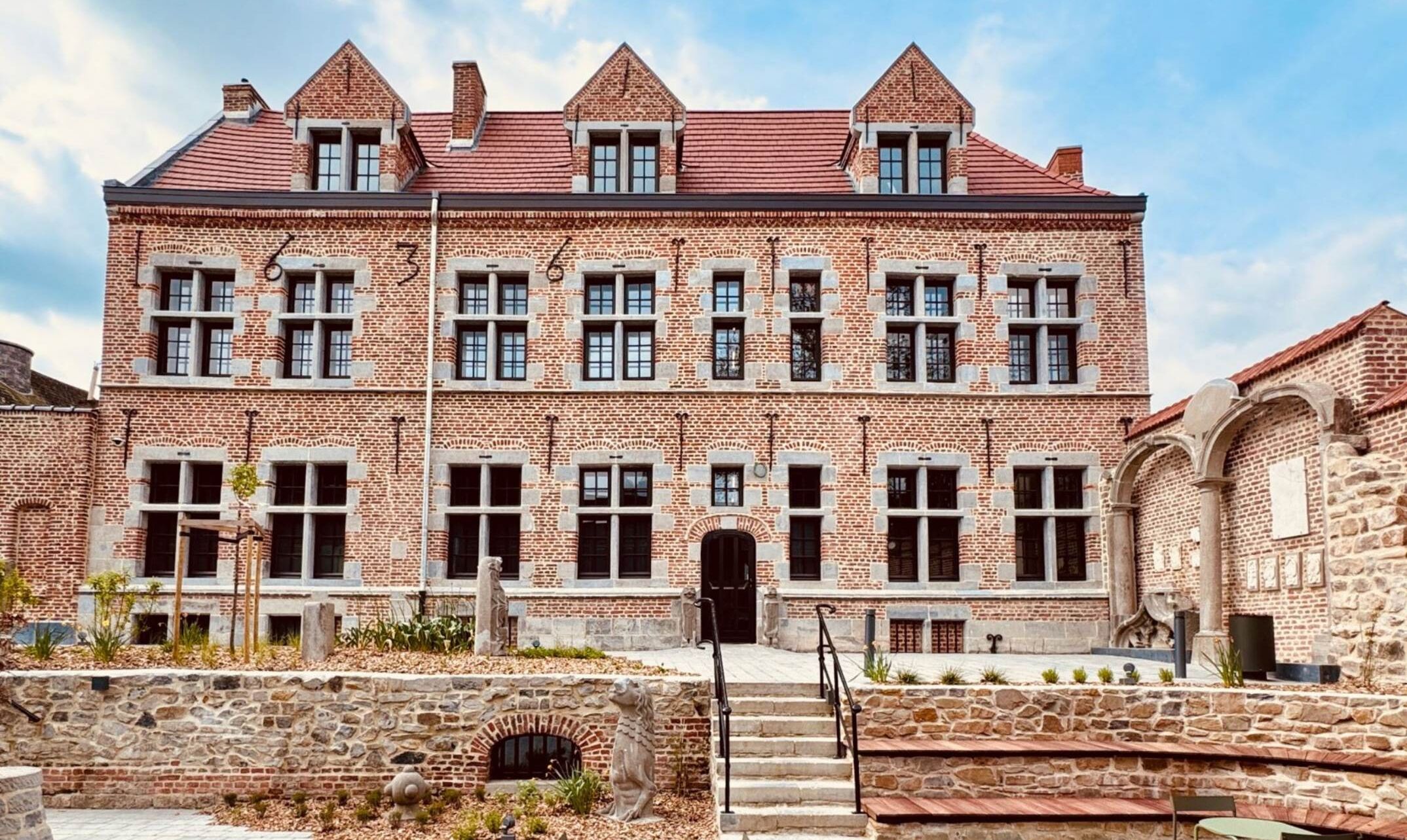 Een groot, meerlaags bakstenen gebouw met een symmetrische gevel, meerdere ramen en een centrale ingang.